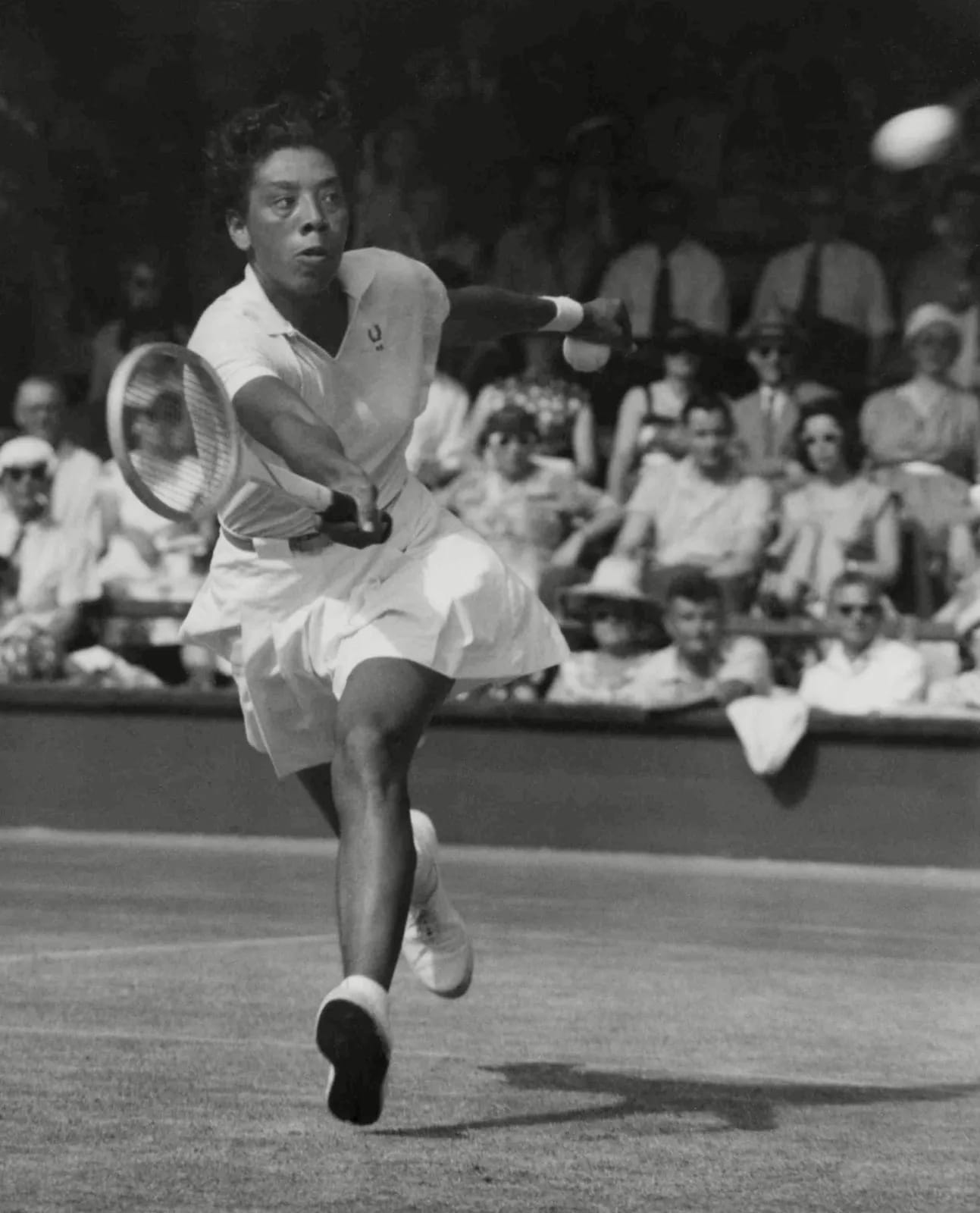 a black and white photo of the Black tennis legend Althea Gibson mid game