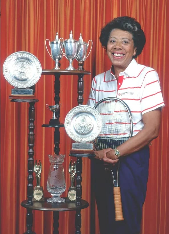 a photo of the Black tennis legend Althea Gibson standing in front of her many awards