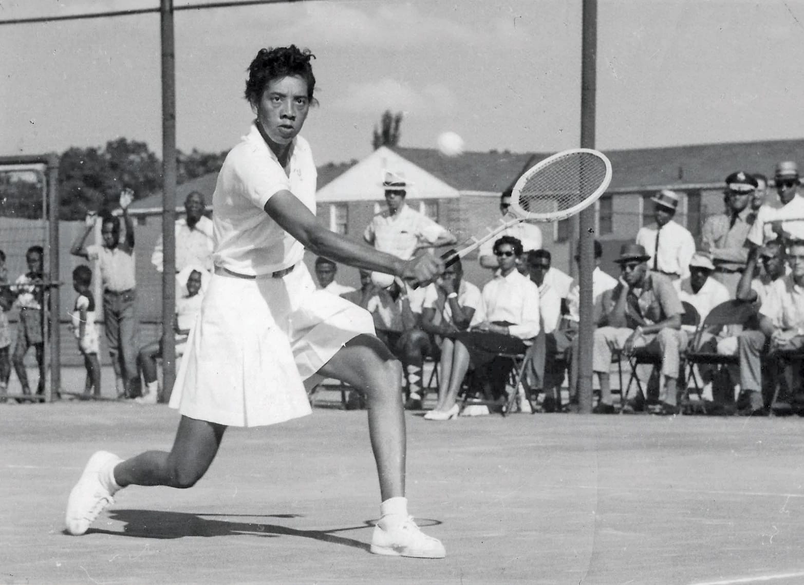 a black and white photo of the Black tennis legend Althea Gibson mid volley