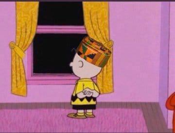 Charlie Brown wears a kente kufi and stares out of the window.