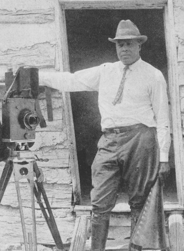 A black and white photo of filmmaker Oscar Micheaux with his film camera, courtesy of the NYPL