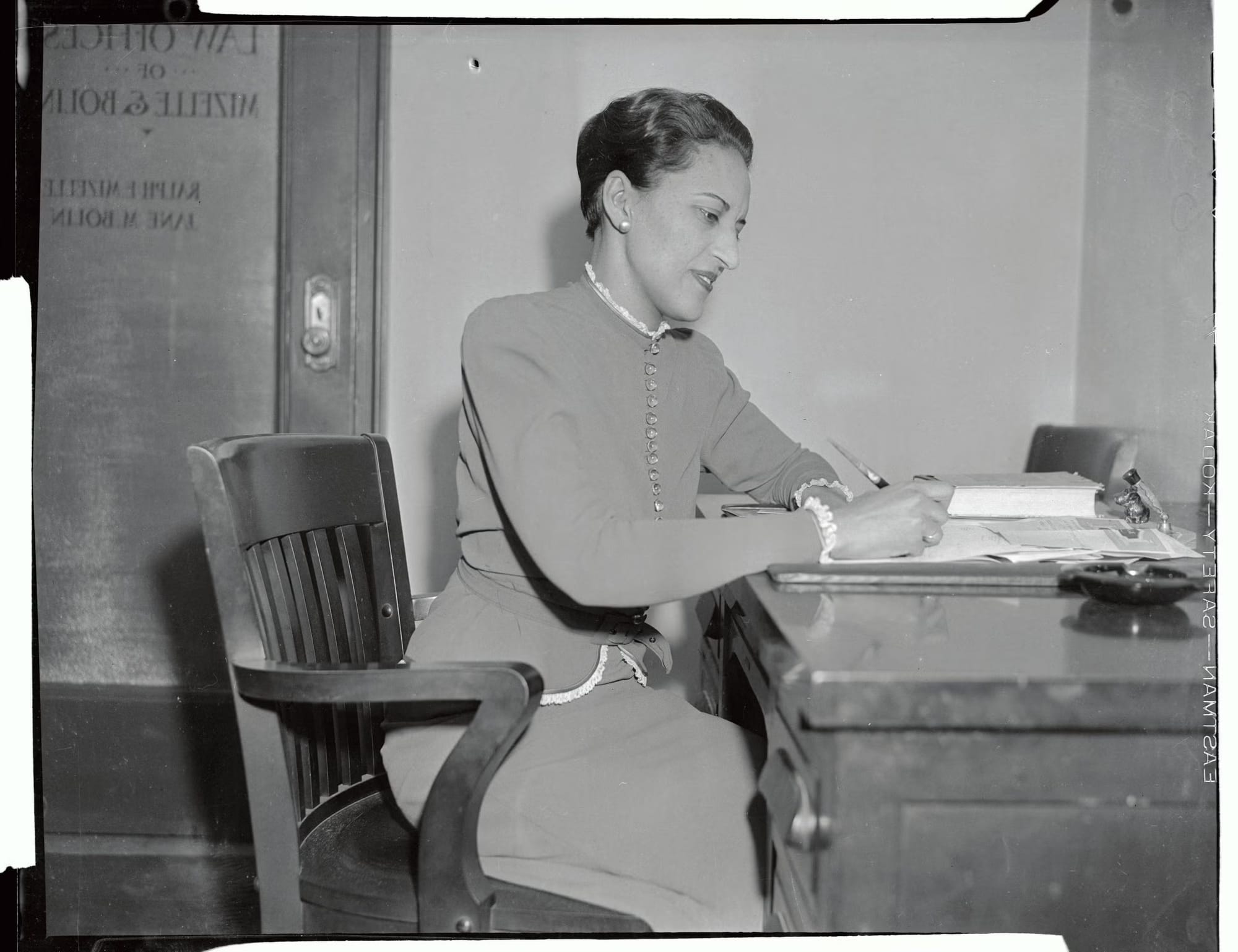 A black and white photo of Jane Bolin sitting at her desk, writing in her office. Courtesy of Bettmann Archives and Getty Images.
