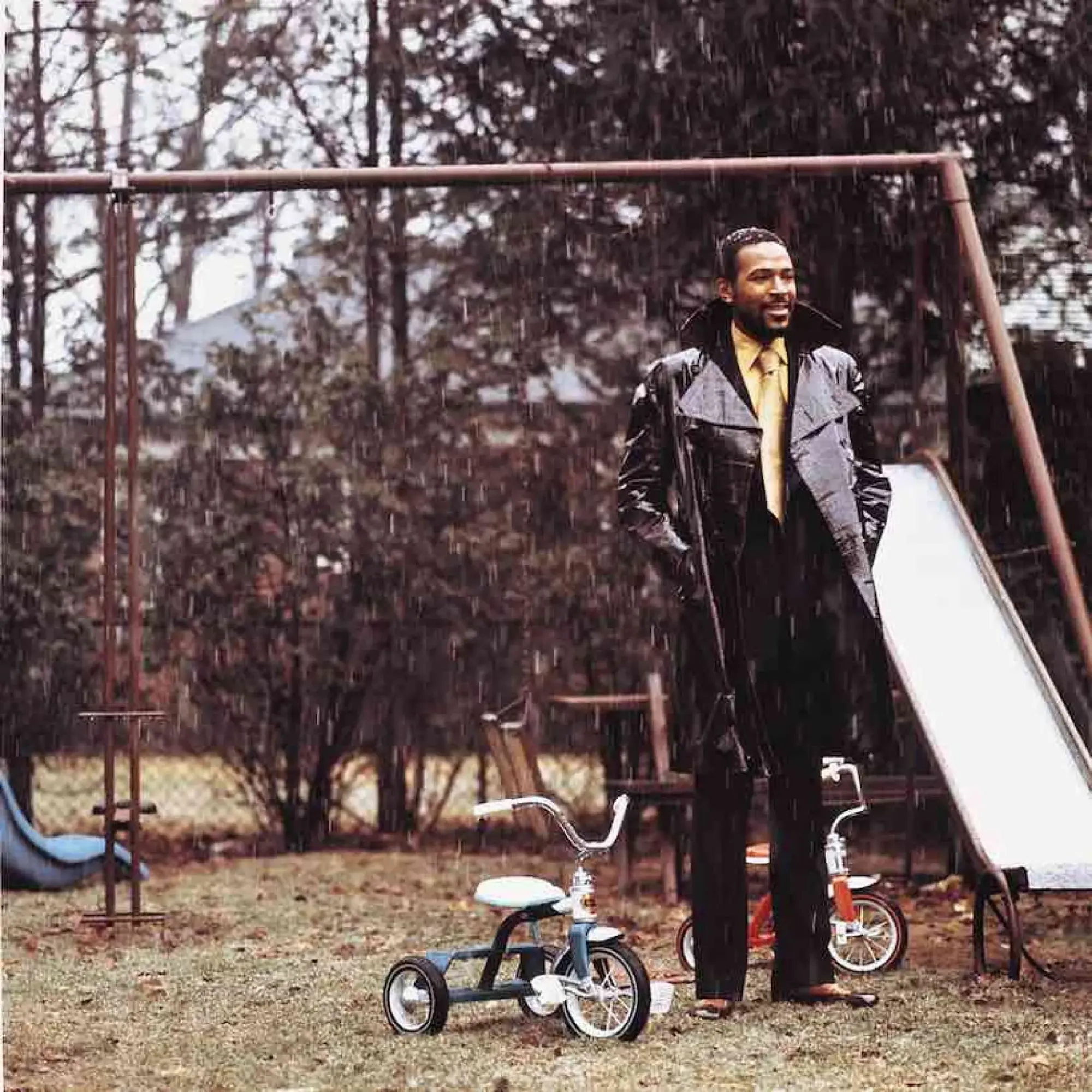 an outtake from the what's going on photoshoot. marvin gaye stands nexts to a kid's playset in the rain