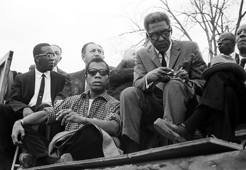 a black and white photo of james baldwin and bayard rustin in conversation