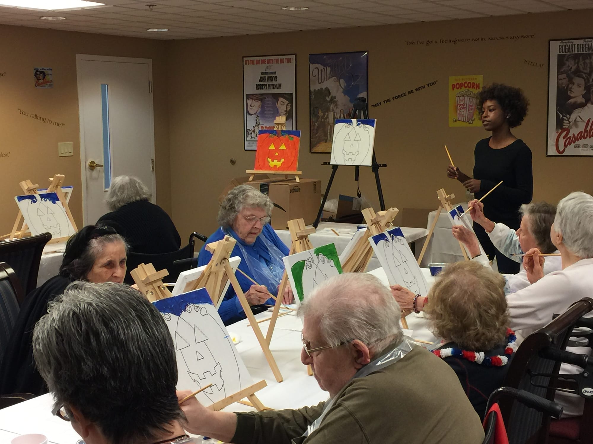 Alleanna teaches senior citizens how to paint a jack o lantern.